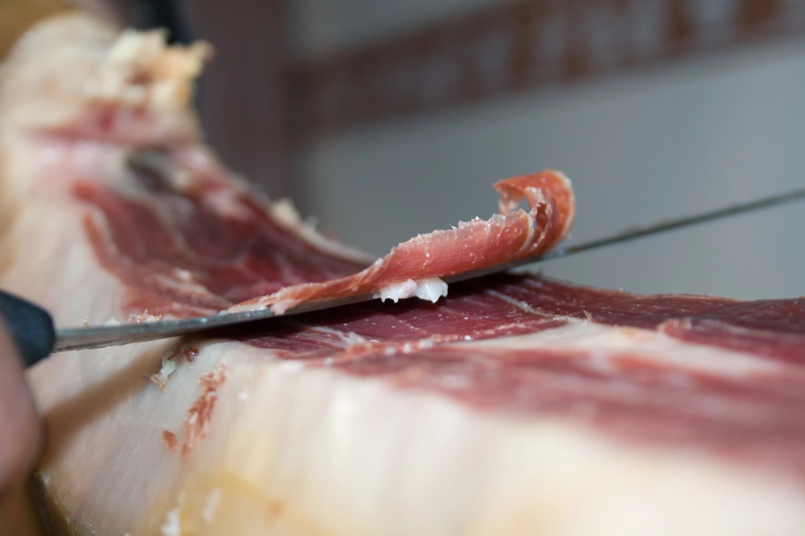 Cuchillo jamonero sacando una loncha fina de jamón ibérico