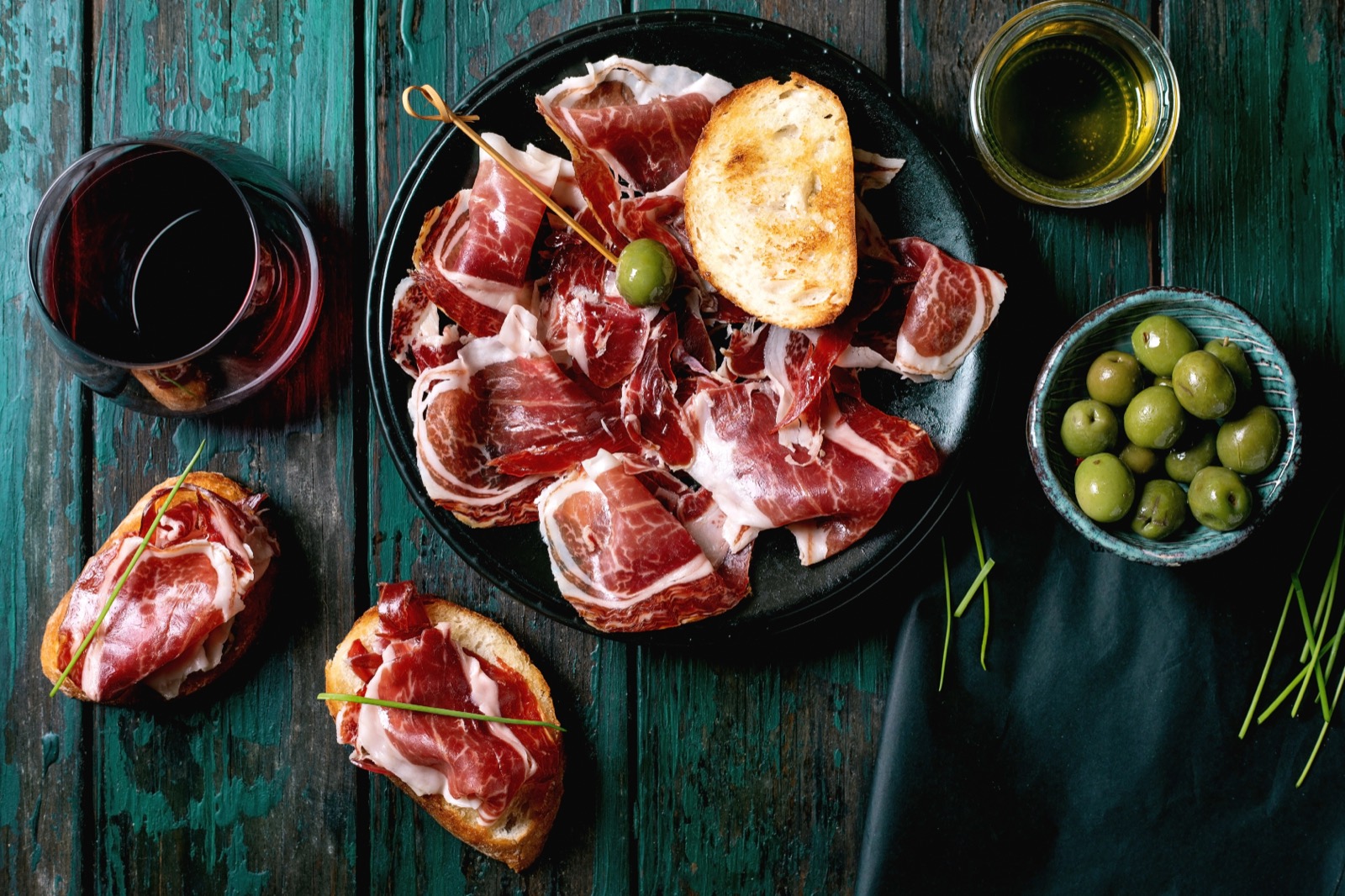 Plato de jamón ibérico con tostas, aceitunas, aceite y vino tinto