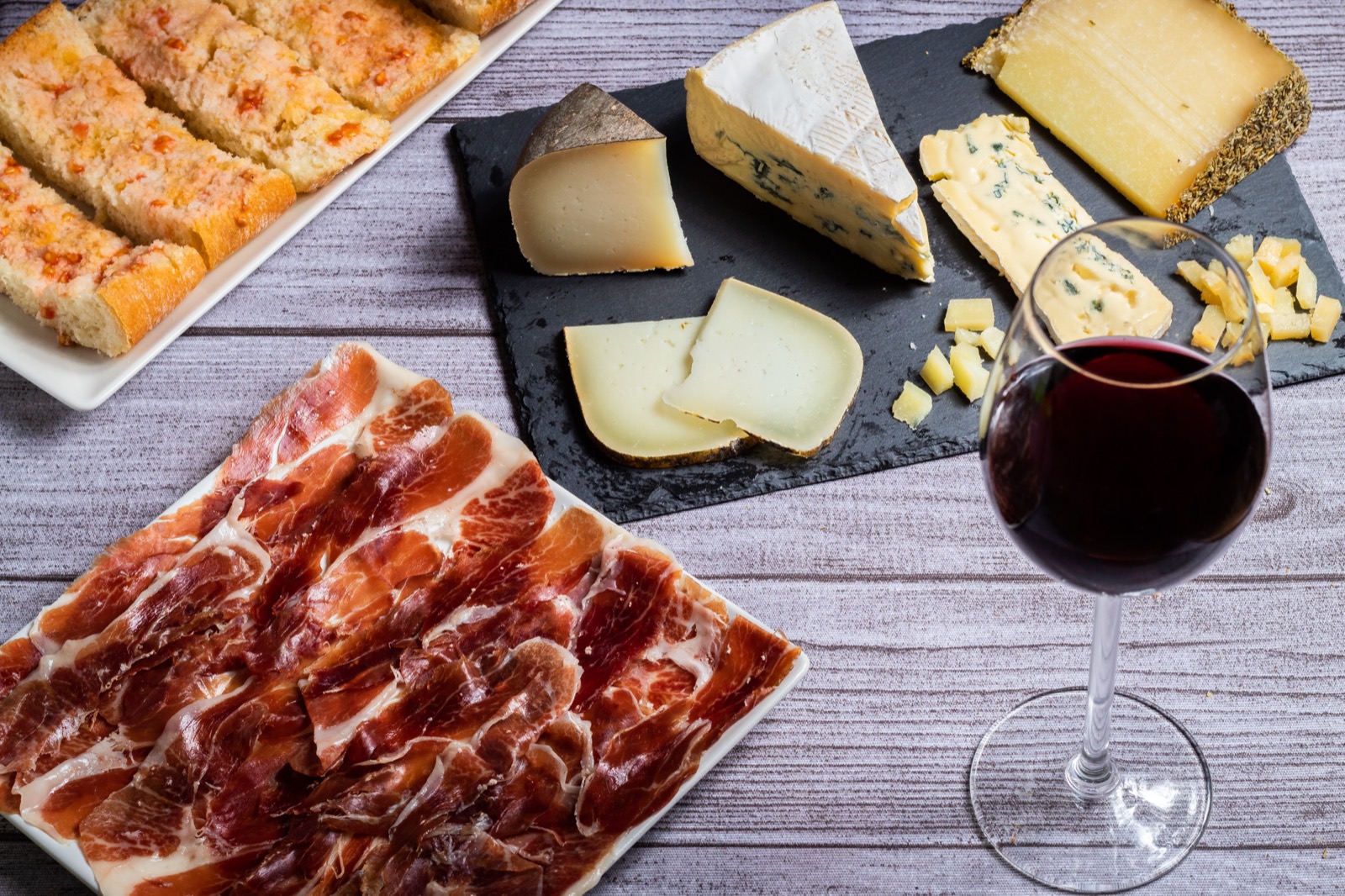 Jamón ibérico, tabla de quesos y copa de vino tinto