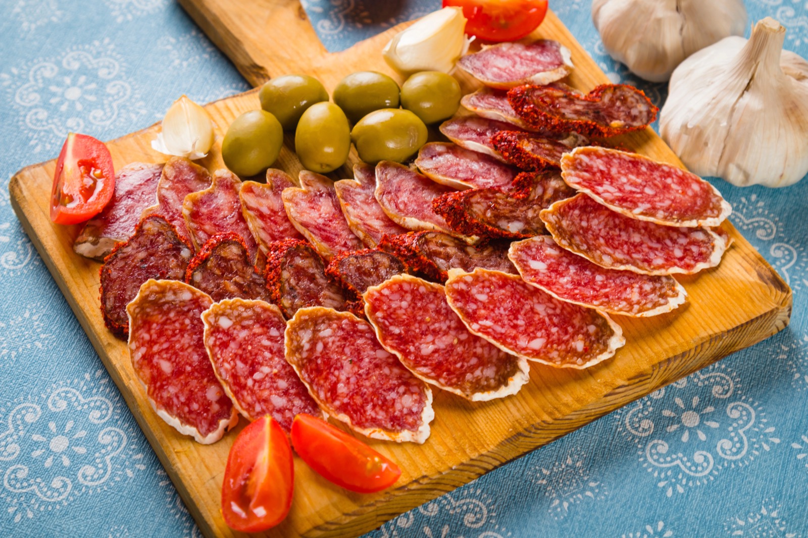 Tabla de madera con salchichón ibérico, aceitunas, tomate y ajo